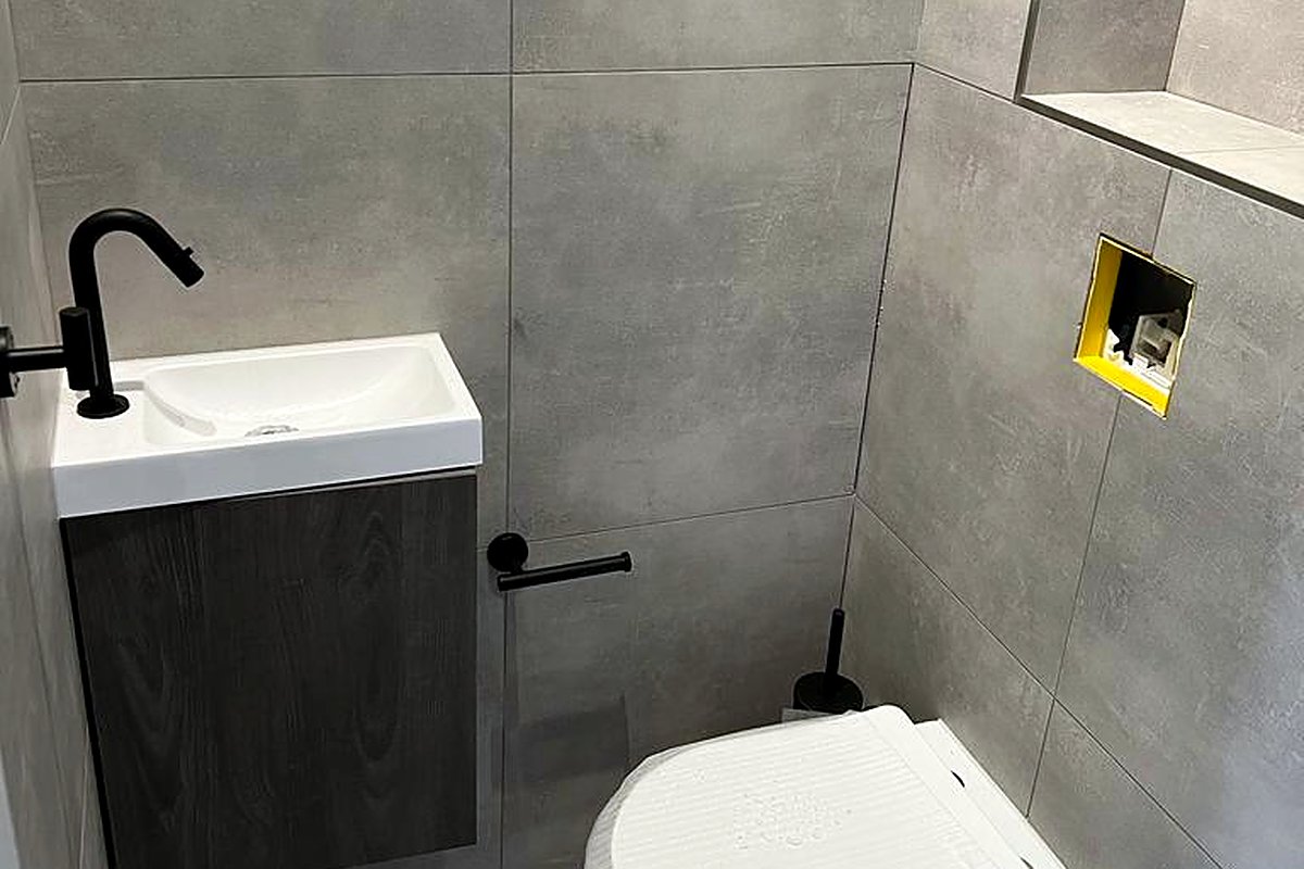 Toilet met houten meubel en wanden in grijze betonlook